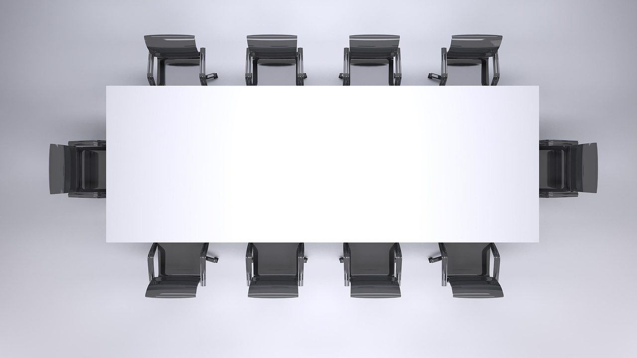A newly appointed corporate manager sitting in a conference room speaking thoughtfully with team members.