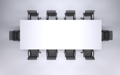 A newly appointed corporate manager sitting in a conference room speaking thoughtfully with team members.