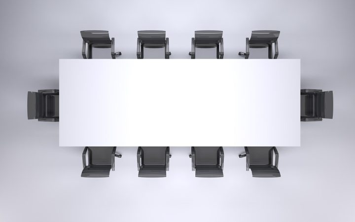 A newly appointed corporate manager sitting in a conference room speaking thoughtfully with team members.