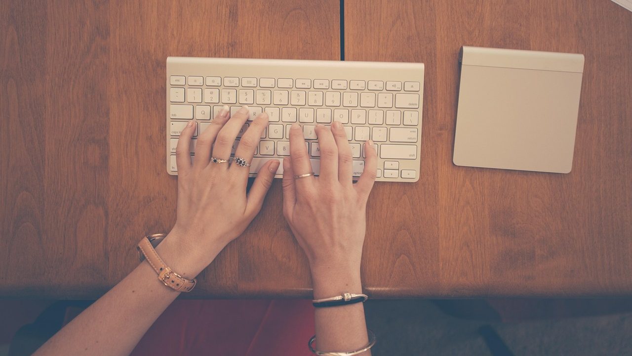 Close-up of a person using an ergonomic under desk keyboard tray in a home office.