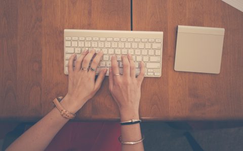 Close-up of a person using an ergonomic under desk keyboard tray in a home office.