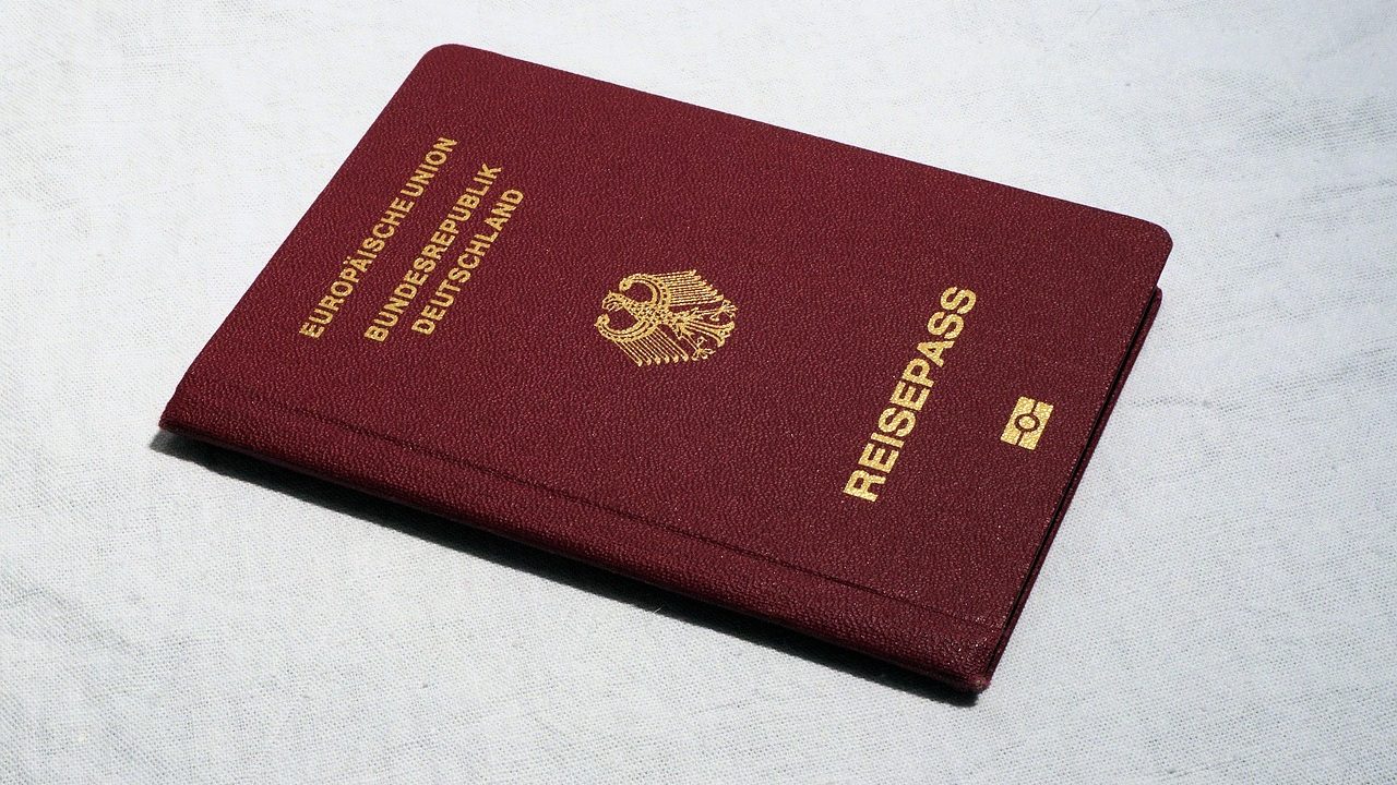US passport sitting on a wooden desk with travel documents and passport photos.