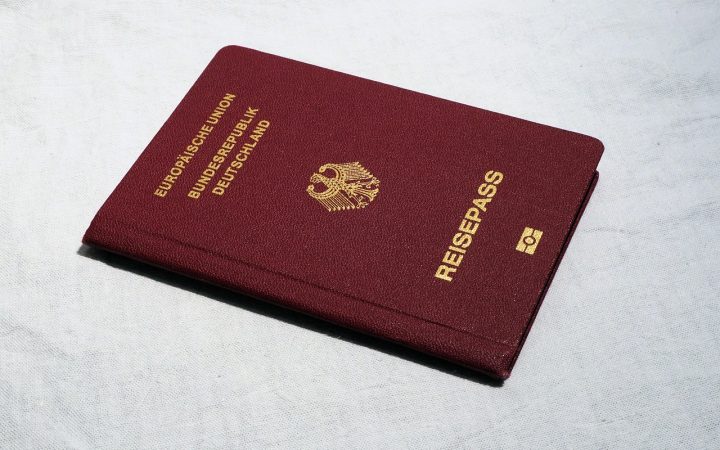 US passport sitting on a wooden desk with travel documents and passport photos.