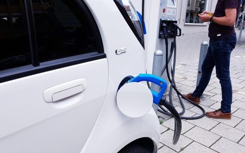A modern electric vehicle charging in a home garage with a wall-mounted Level 2 EV charger.