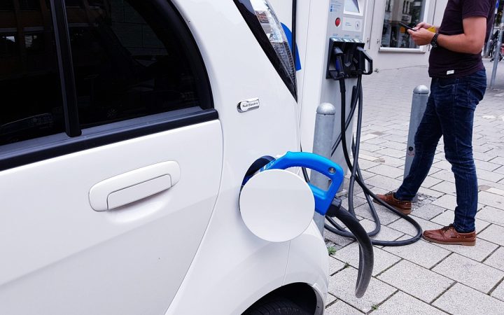 A modern electric vehicle charging in a home garage with a wall-mounted Level 2 EV charger.