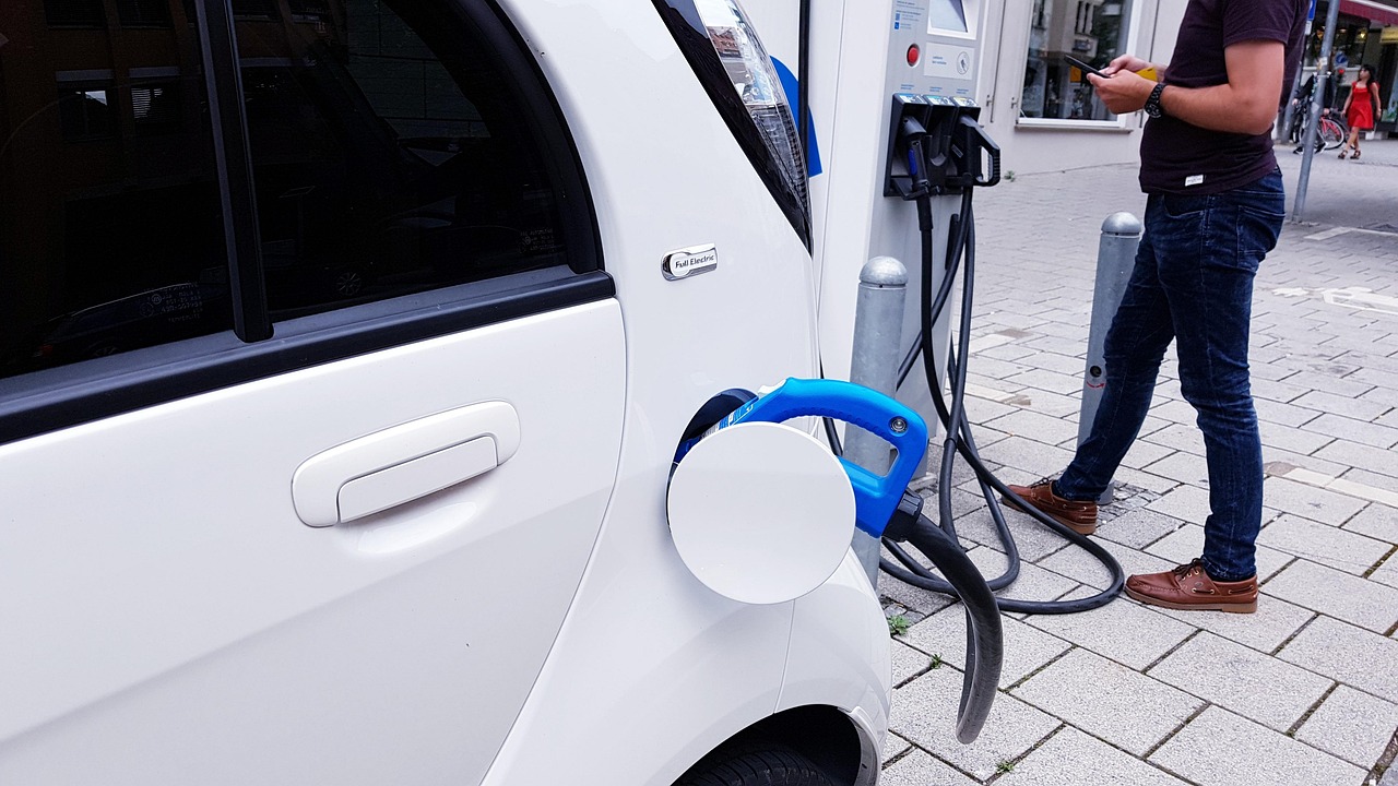 A modern electric vehicle charging in a home garage with a wall-mounted Level 2 EV charger.