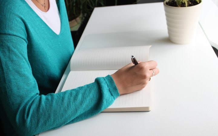 A person sitting at a wooden desk filling out official state paperwork.