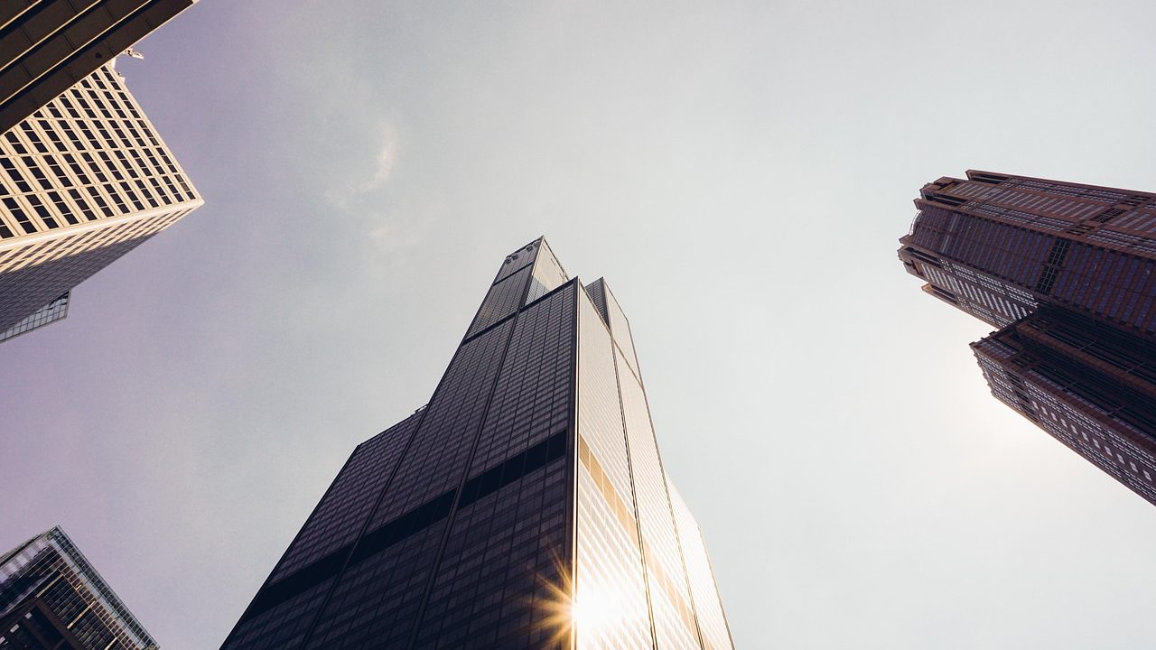 Corporate employee reflecting at a modern desk near a high-rise window during a restructuring period.