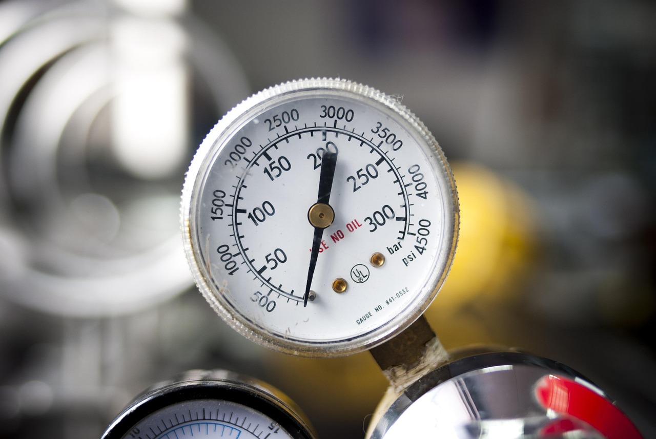 A brass water pressure gauge connected to a residential faucet showing water pressure reading.