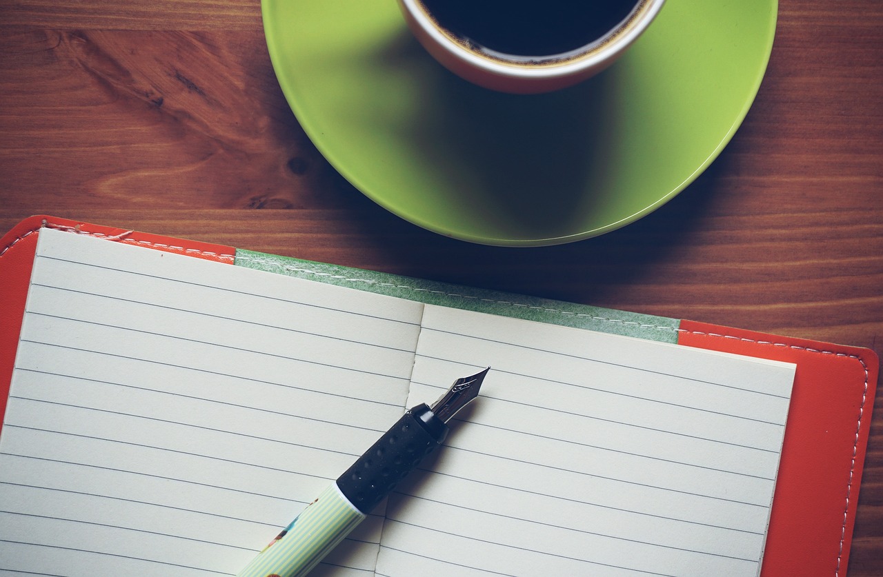 An open notebook and a keyboard on a clean wooden workspace