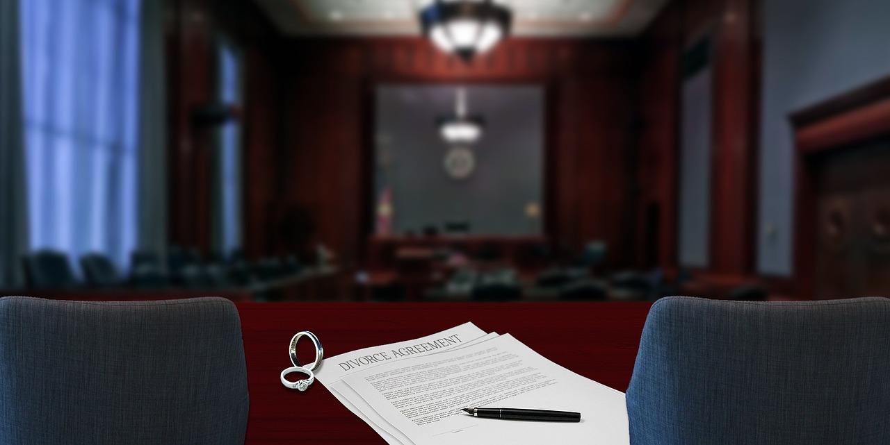 An empty US courtroom featuring a wooden jury box, counsel tables, and the judge's bench.