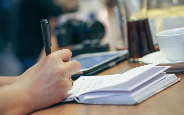 A peaceful household desk setup with a notebook, budget notes, and a digital banking app on a smartphone screen.