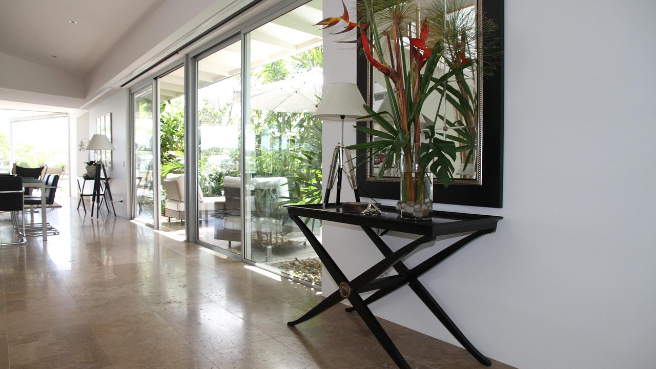 A modern sunlit living room showing window film on one glass pane and a cellular shade on another.