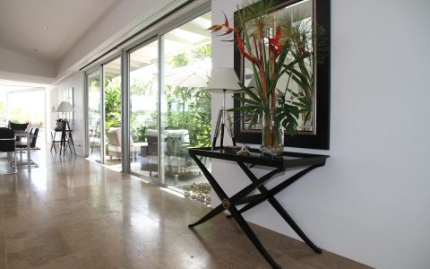 A modern sunlit living room showing window film on one glass pane and a cellular shade on another.