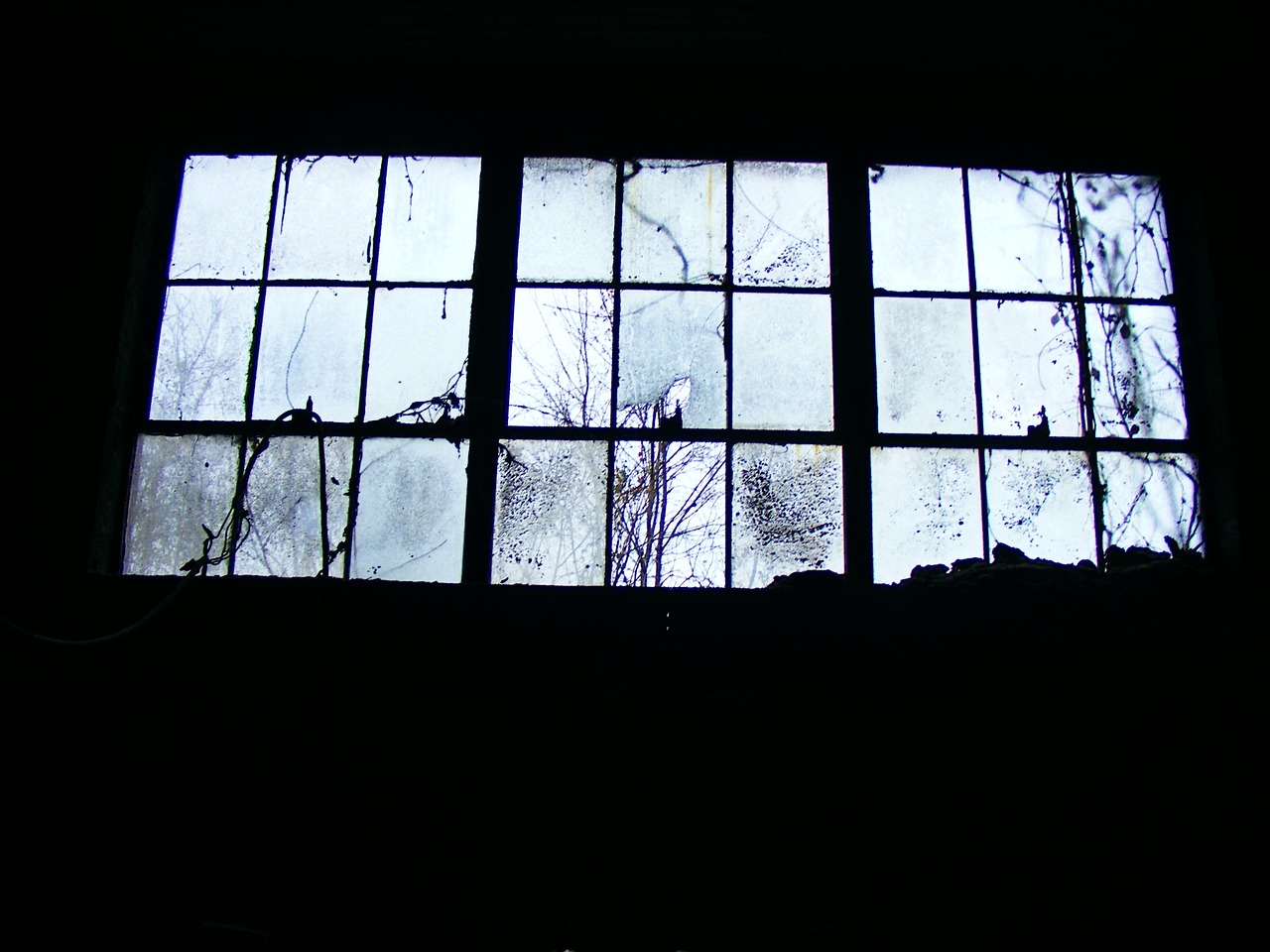 Close-up of hands applying foam weatherstripping tape to a wooden window frame.
