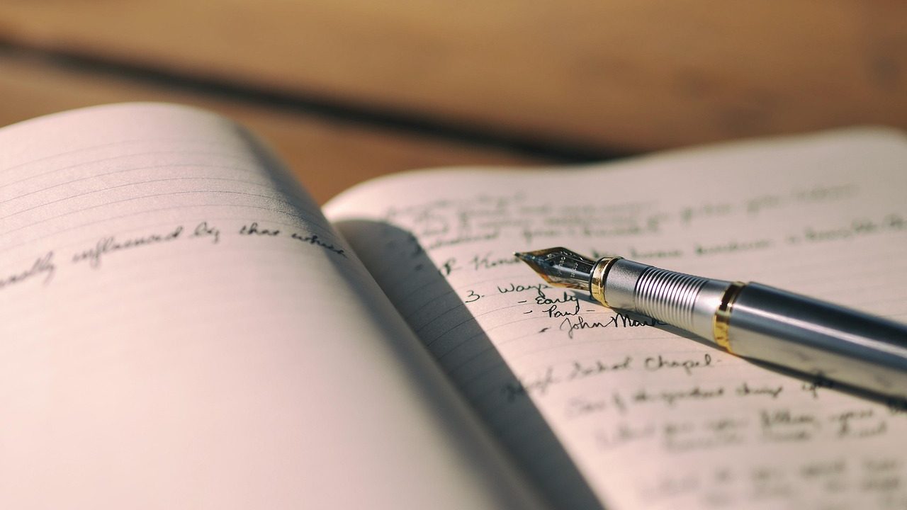 A person writing financial notes in a ledger with a pen.