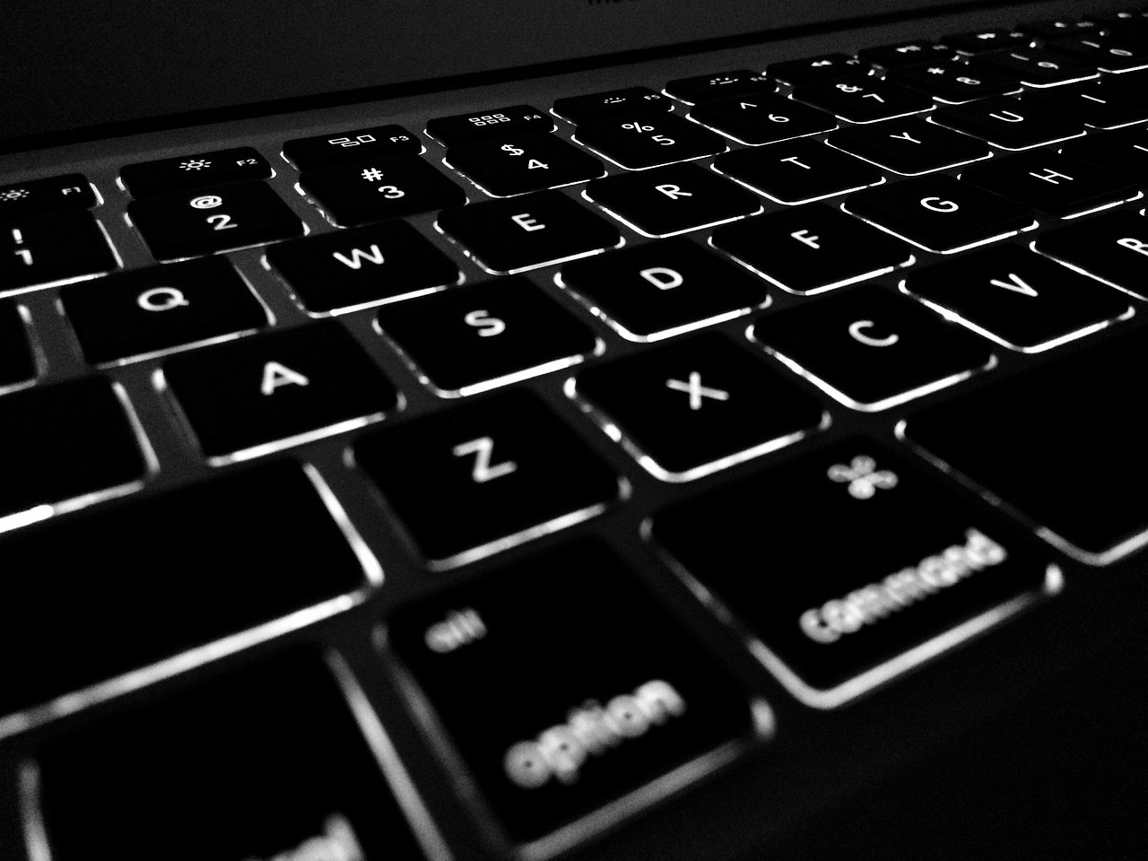 Close-up of hands typing on a modern laptop keyboard in a home office.