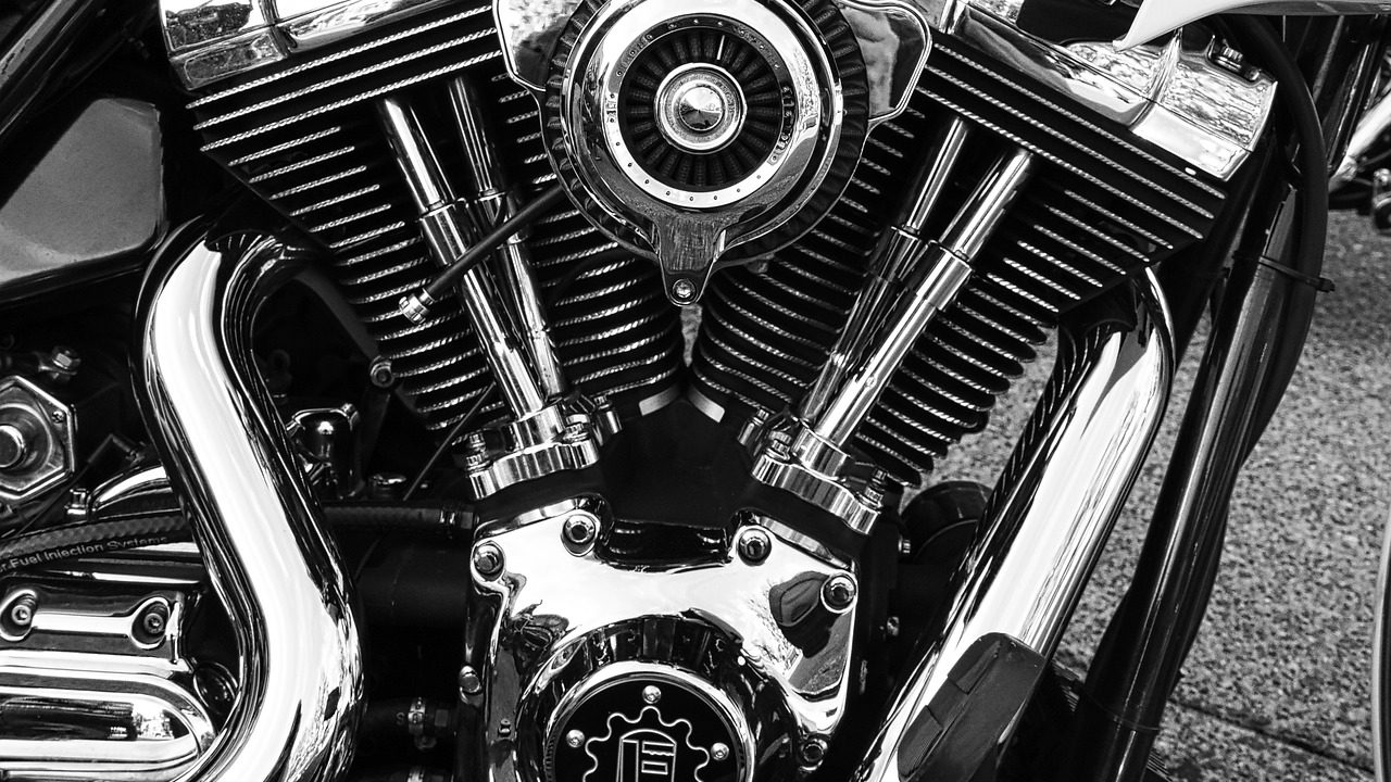 A close-up view of a mechanic inspecting a motorcycle engine component.