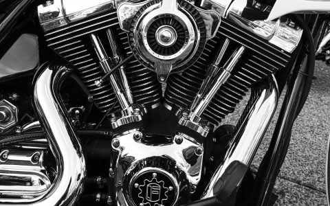 A close-up view of a mechanic inspecting a motorcycle engine component.
