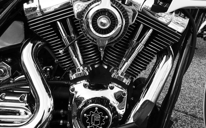A close-up view of a mechanic inspecting a motorcycle engine component.
