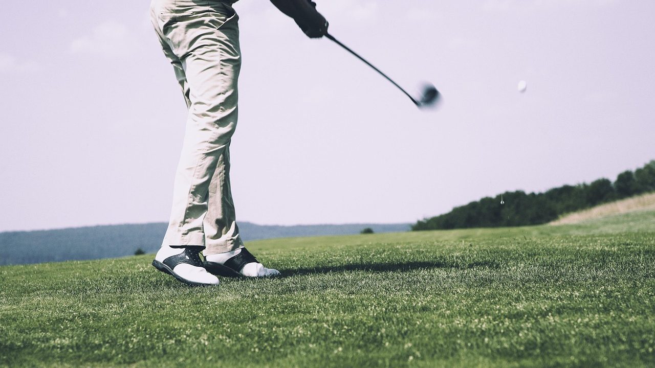 A golfer closely examining the club face of a pre-owned iron.
