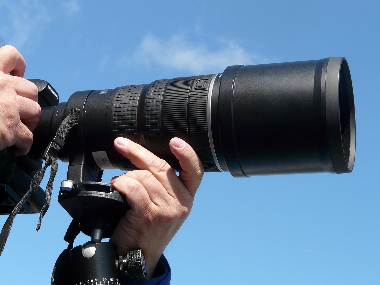 Remote worker adjusting focus on a DSLR camera mounted for video conferencing.