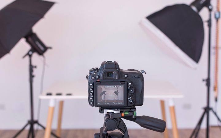 A modern home office desk featuring a mirrorless camera mounted on a tripod connected to a video capture card.