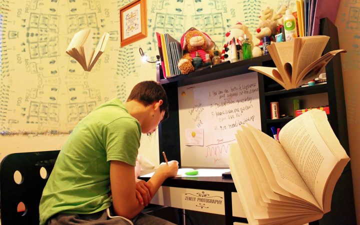 College student reviewing a textbook and laptop at a desk