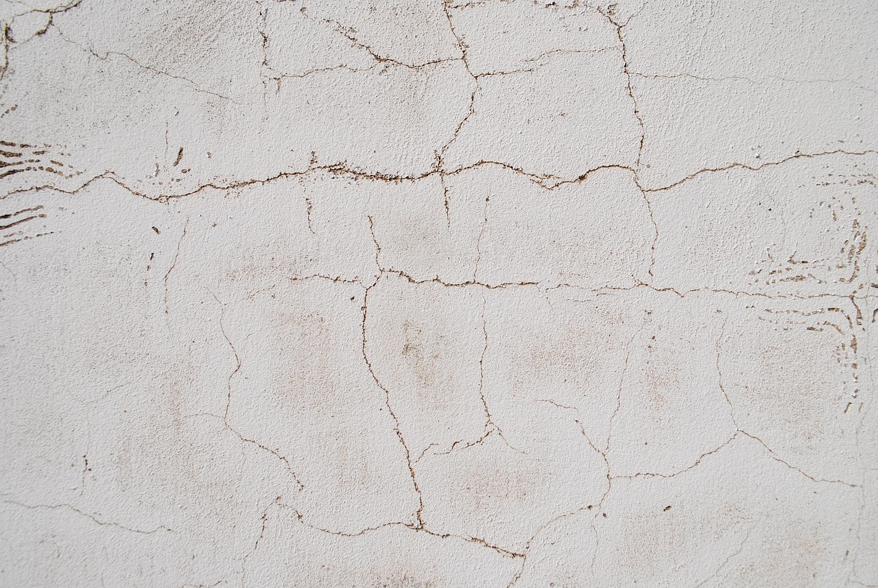 Close-up of a crack gauge tool measuring a hairline crack on a concrete wall