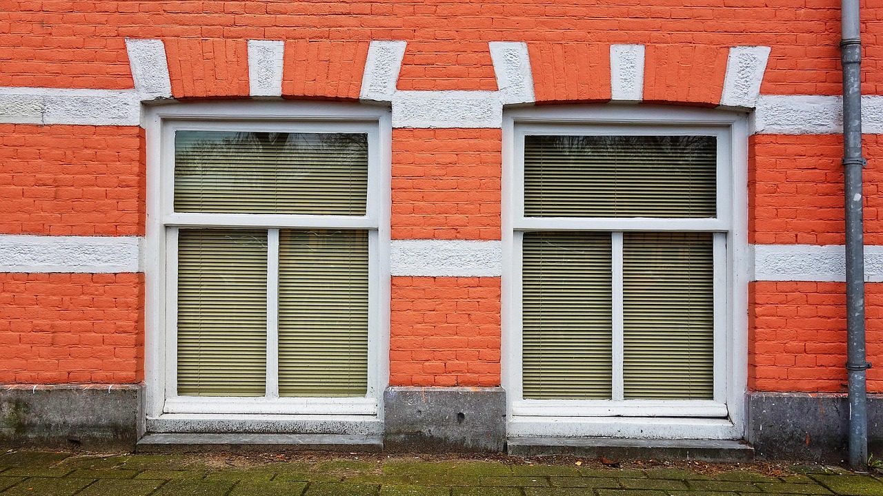A weathered concrete window well showing signs of water seepage and staining against a house foundation.