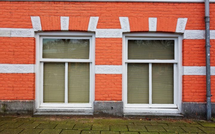 A weathered concrete window well showing signs of water seepage and staining against a house foundation.