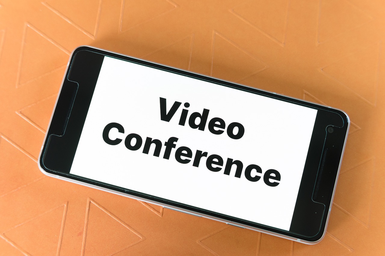 Professional working on a laptop during a video conference using an external desktop microphone.