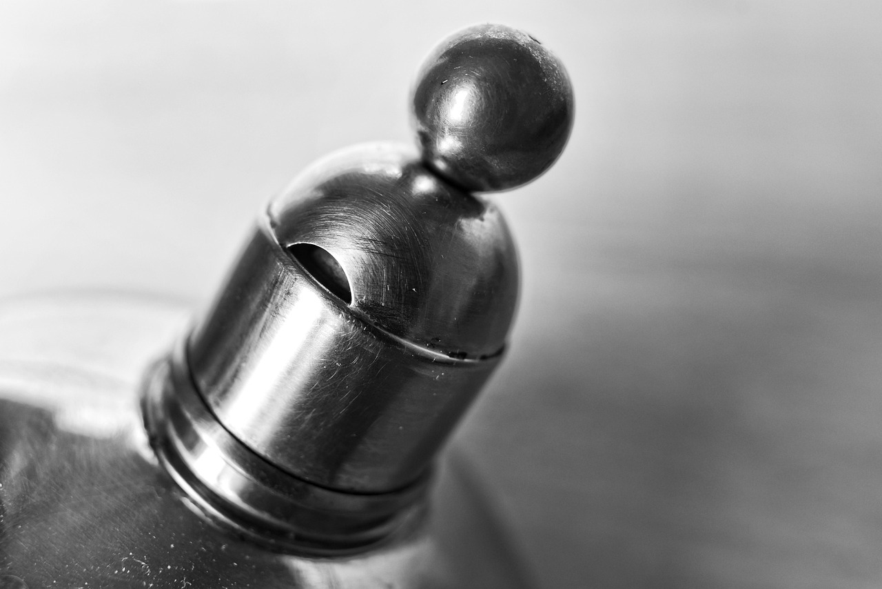 A traditional stainless steel whistling tea kettle sitting on a gas stove burner.