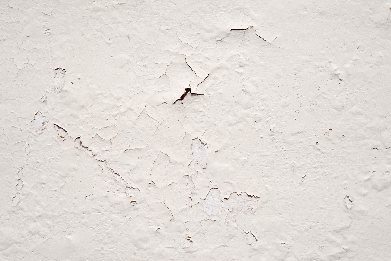 Damaged concrete garage floor showing peeling paint and structural cracks.