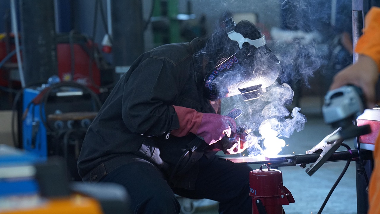 High school student wearing safety gear while practicing welding in a technical education workshop.