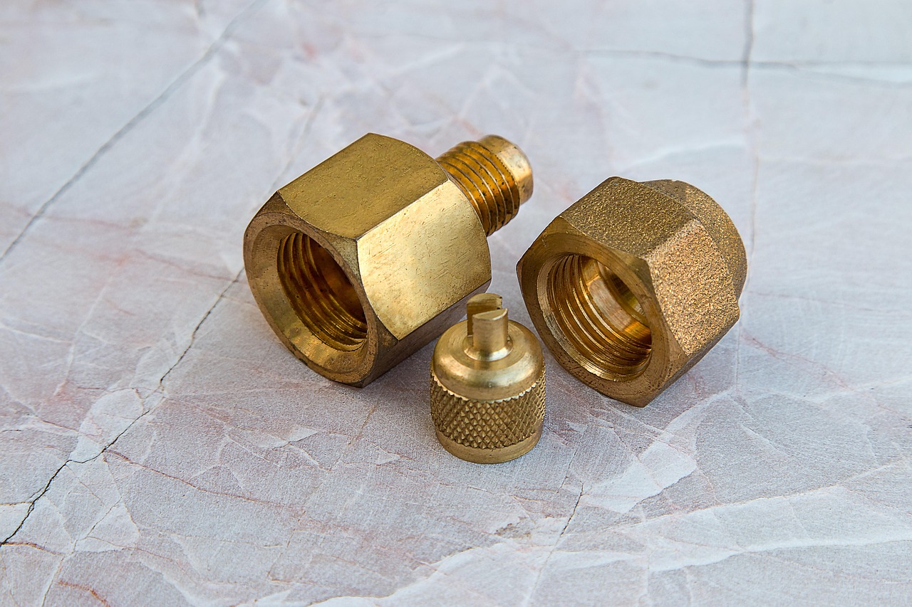 Close up of hands using adjustable wrenches on a brass plumbing valve.