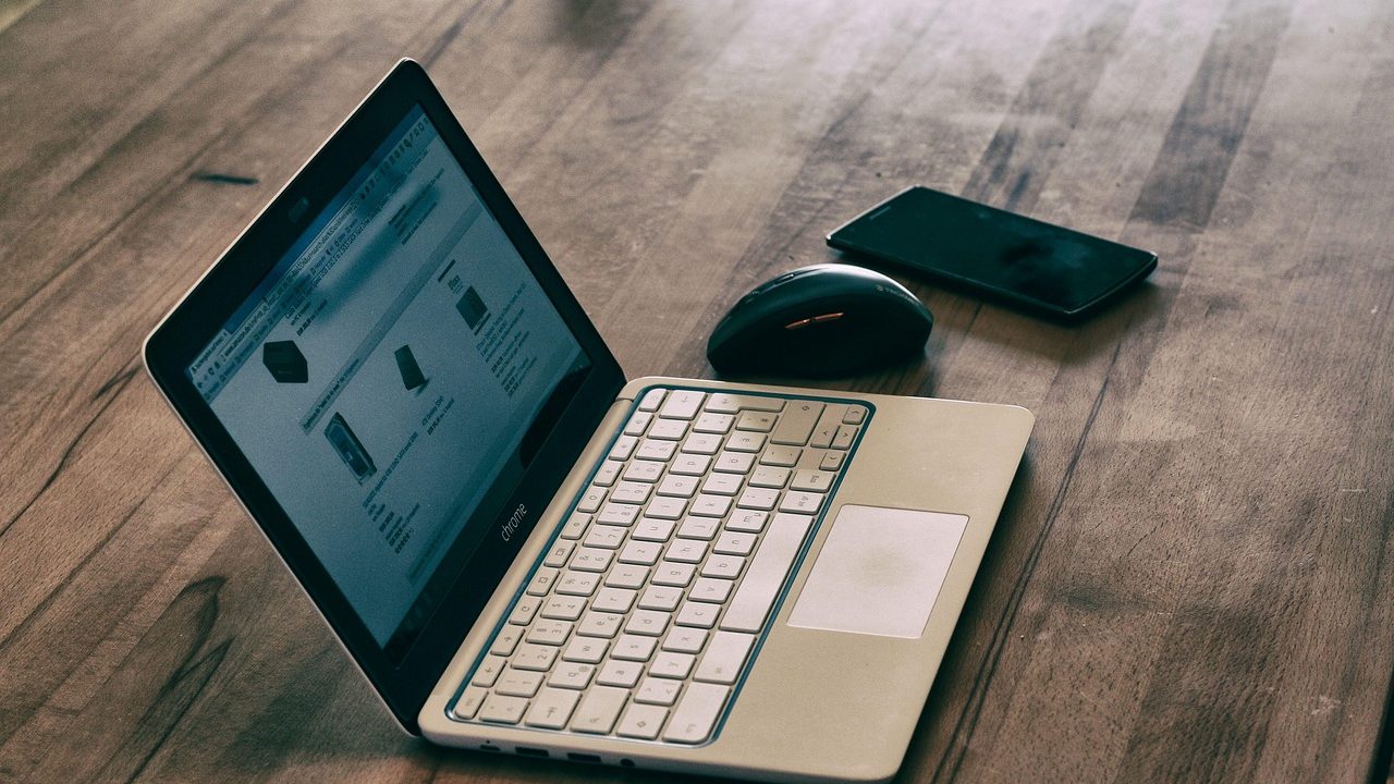 A laptop and smartphone resting on a clean wooden desk setup.