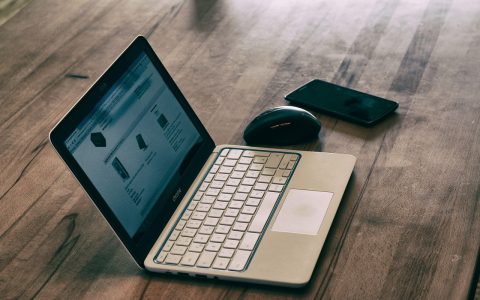 A laptop and smartphone resting on a clean wooden desk setup.
