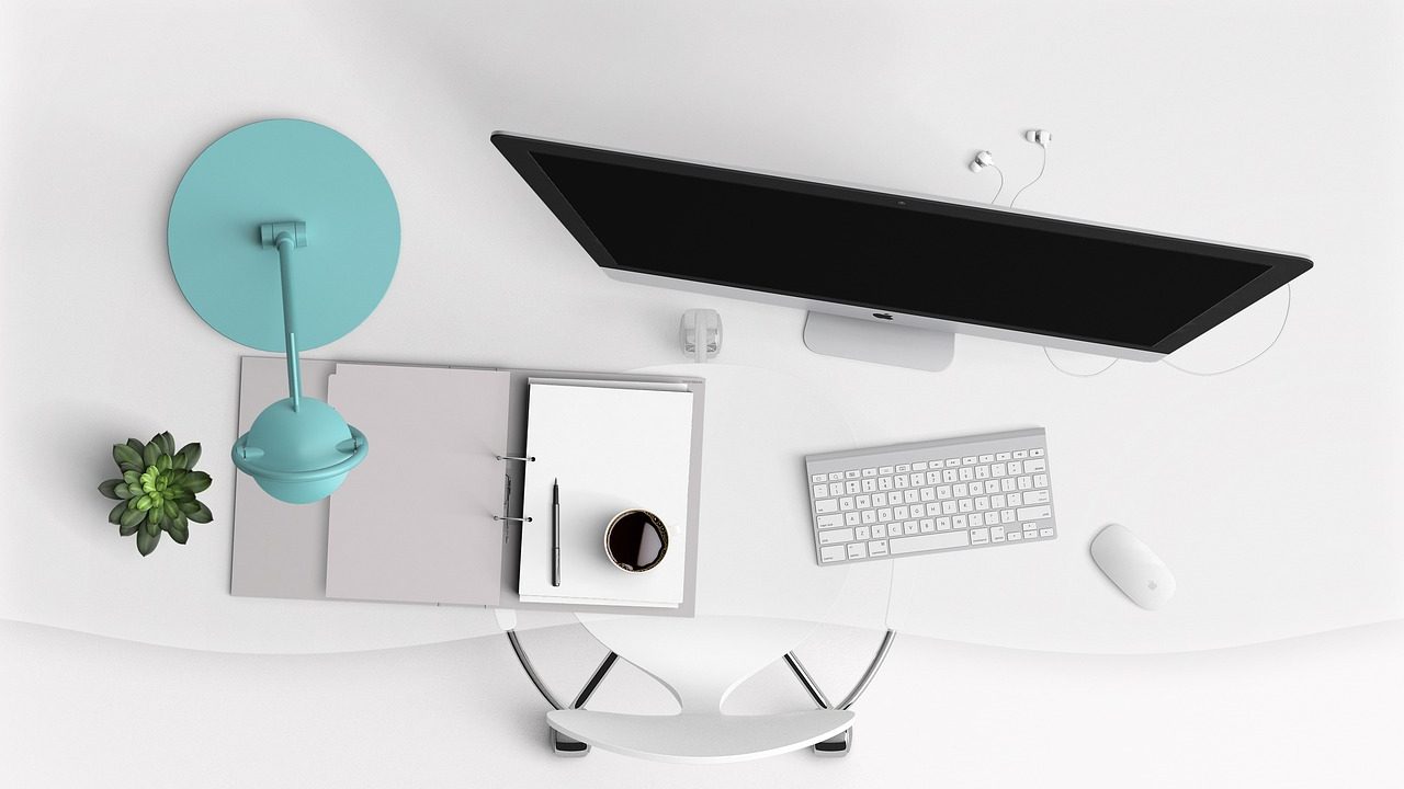 A clean modern home office desk setup illuminated by a sleek monitor light bar mounted above the display.