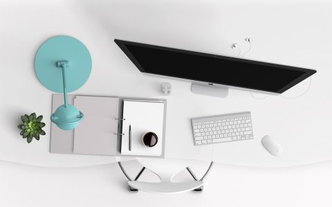 A clean modern home office desk setup illuminated by a sleek monitor light bar mounted above the display.