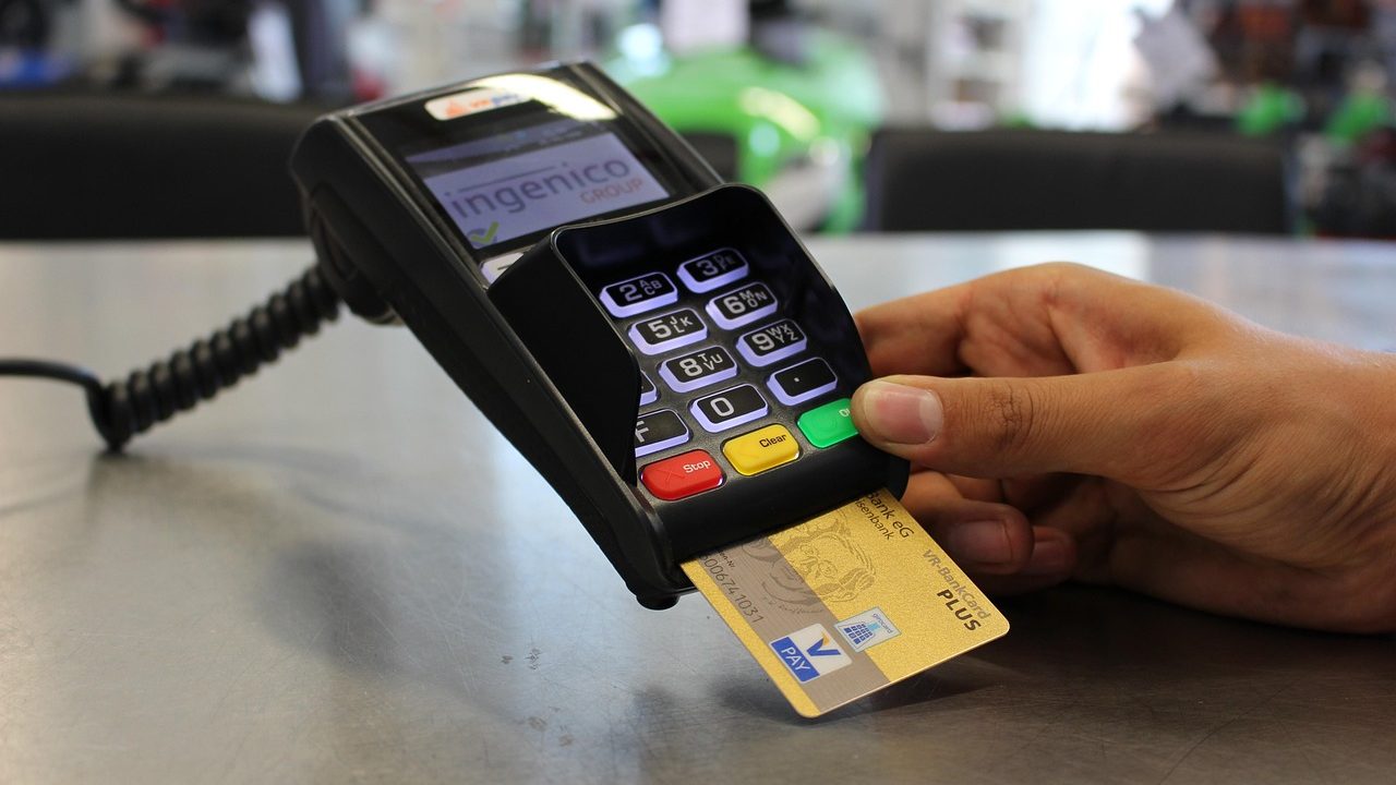 A person reviewing a digital credit card statement on a laptop at a kitchen table.