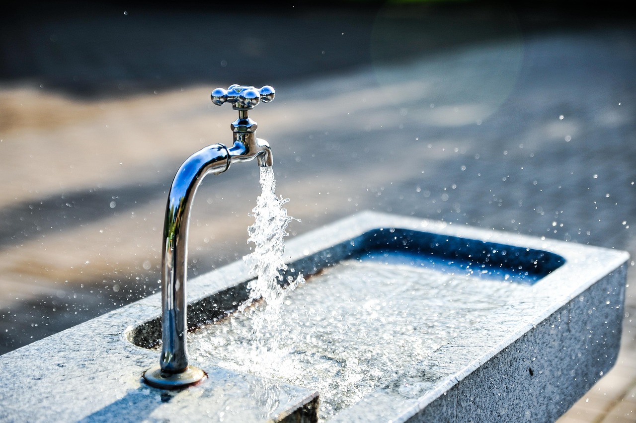 Close-up of a quick-connect faucet adapter attached to a kitchen sink faucet.