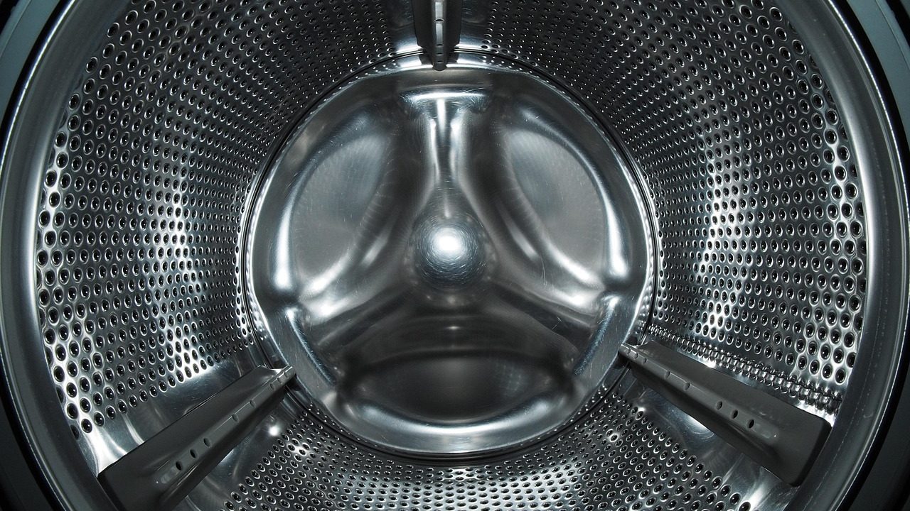 A compact portable washing machine installed in a small apartment bathroom.