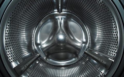 A compact portable washing machine installed in a small apartment bathroom.