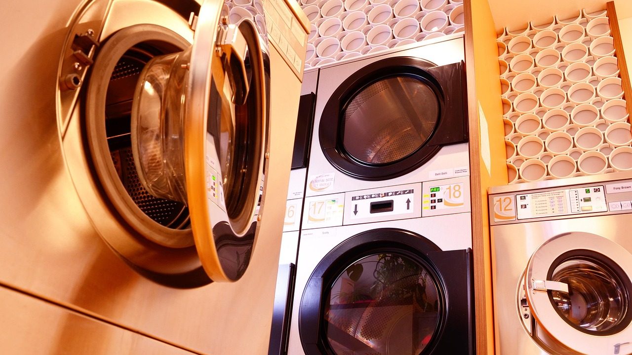 A compact clothes dryer securely installed on a metal wall-mounting bracket in a small laundry area.