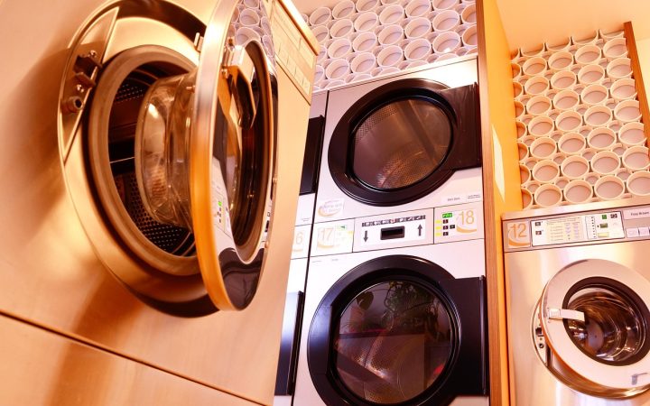 A compact clothes dryer securely installed on a metal wall-mounting bracket in a small laundry area.