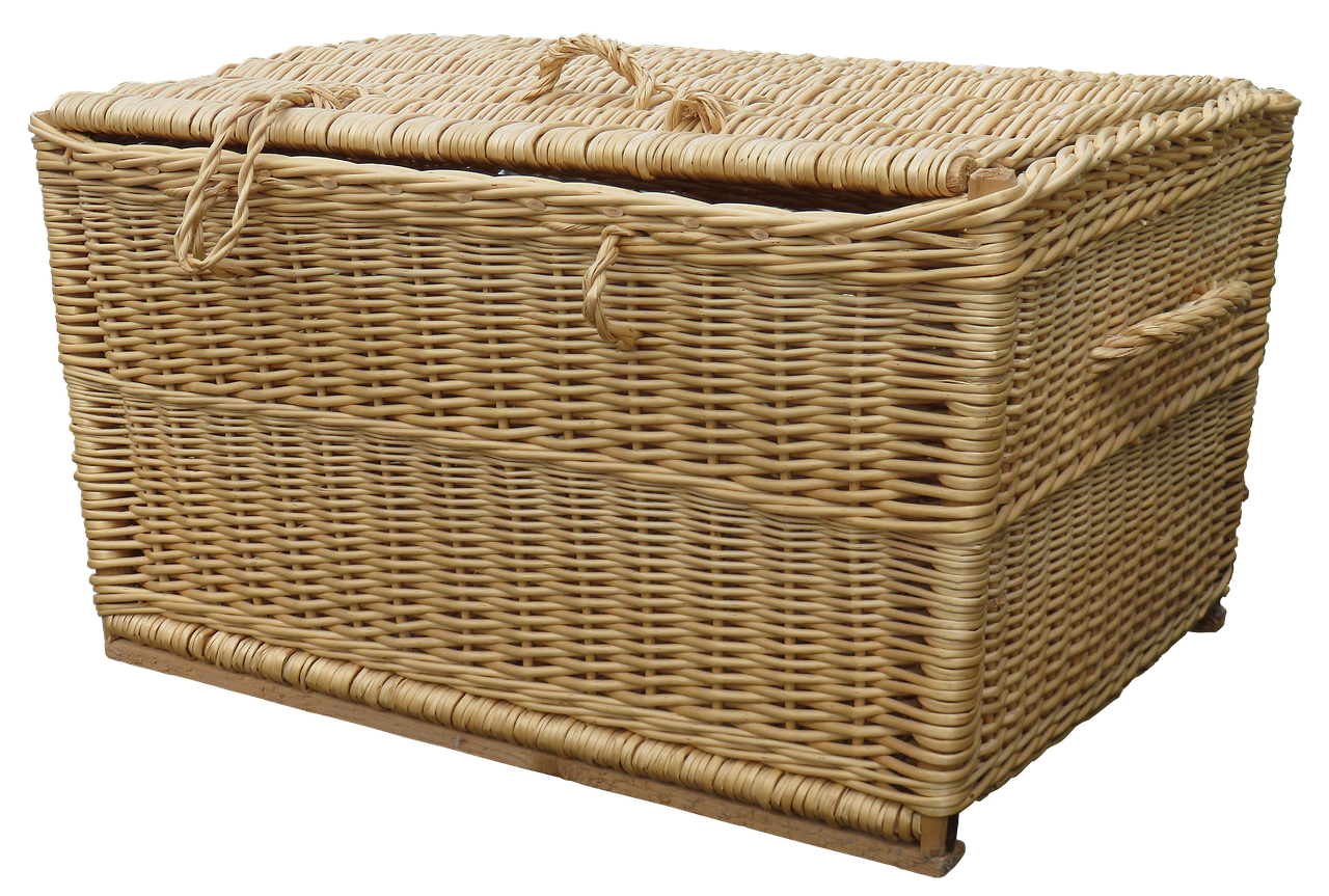 A full laundry basket of freshly folded clothes resting on a wooden tabletop.