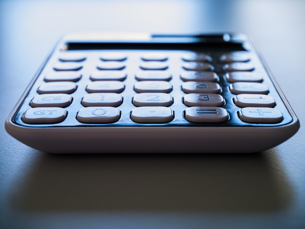 Close-up of a desk setup featuring a laptop and a calculator for auditing recurring subscription expenses.