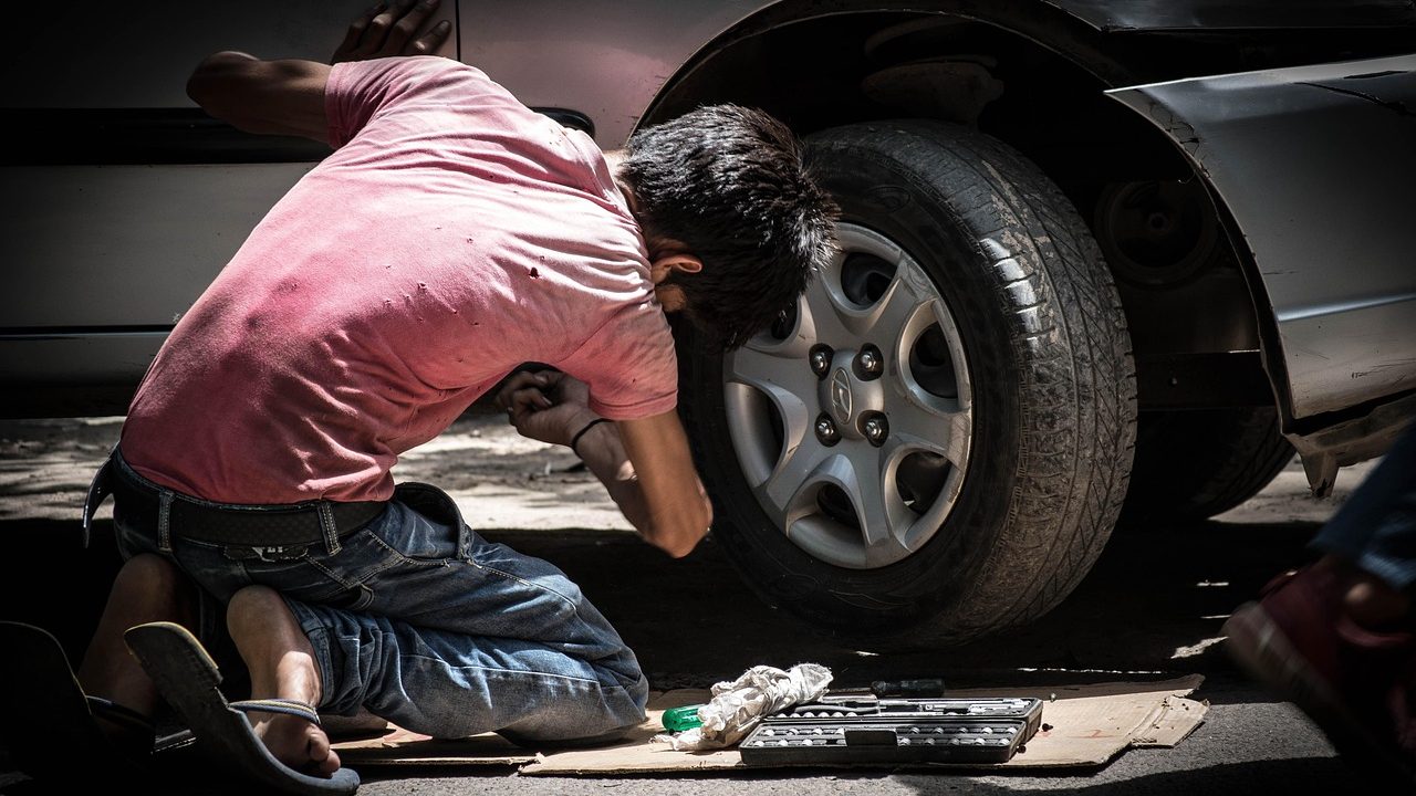Mechanic testing a car battery in a bright workshop