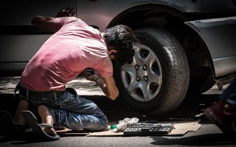 Mechanic testing a car battery in a bright workshop